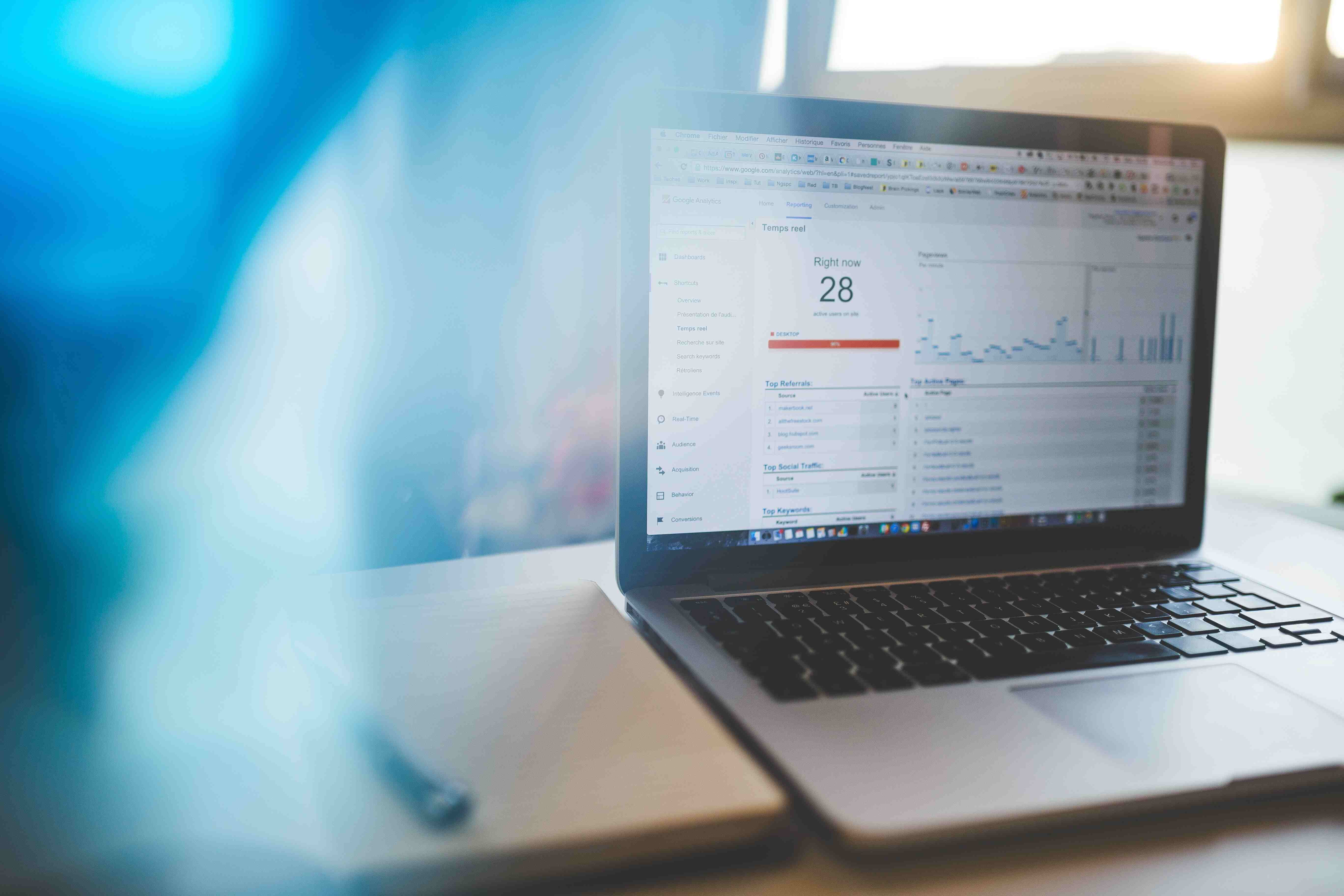 An open Macbook Pro on wooden table with Google Analytics showing on the screen